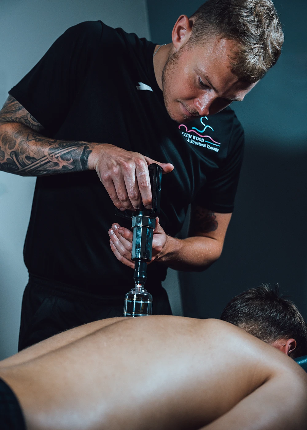 Callum applying a suction cup therapy cup to a male clients back - Callum Wood Sports & Structural Therapy.